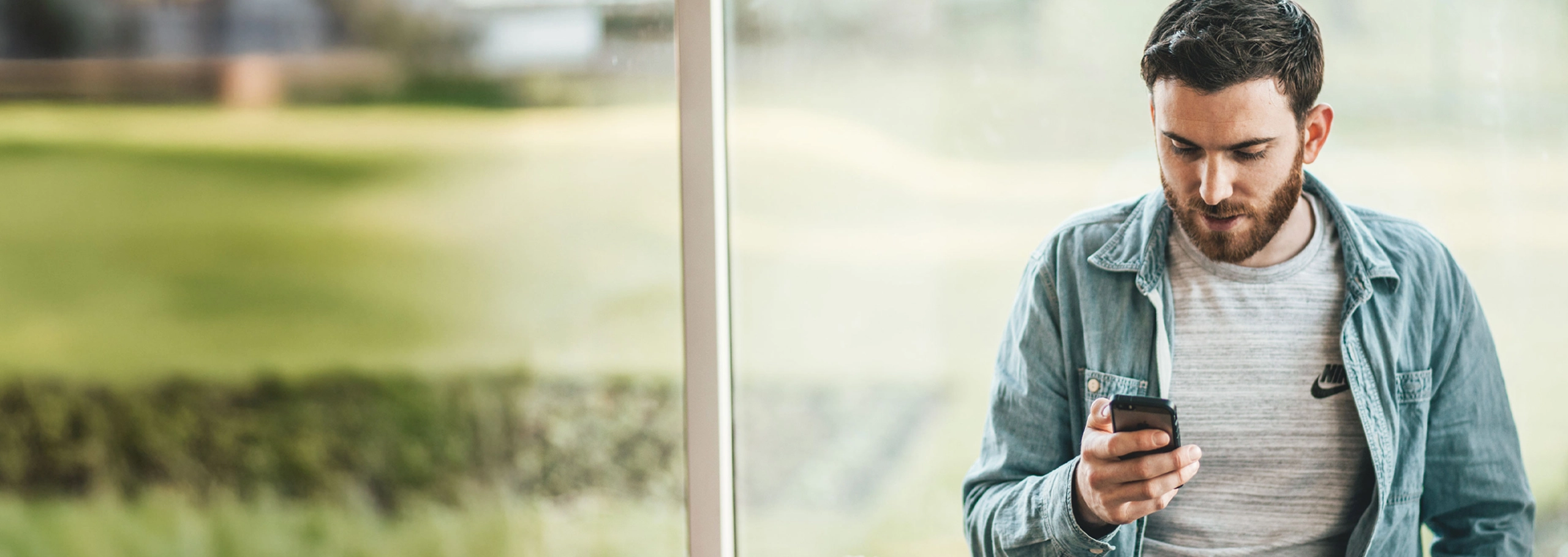 Man sitting in front of a window using his cellphone