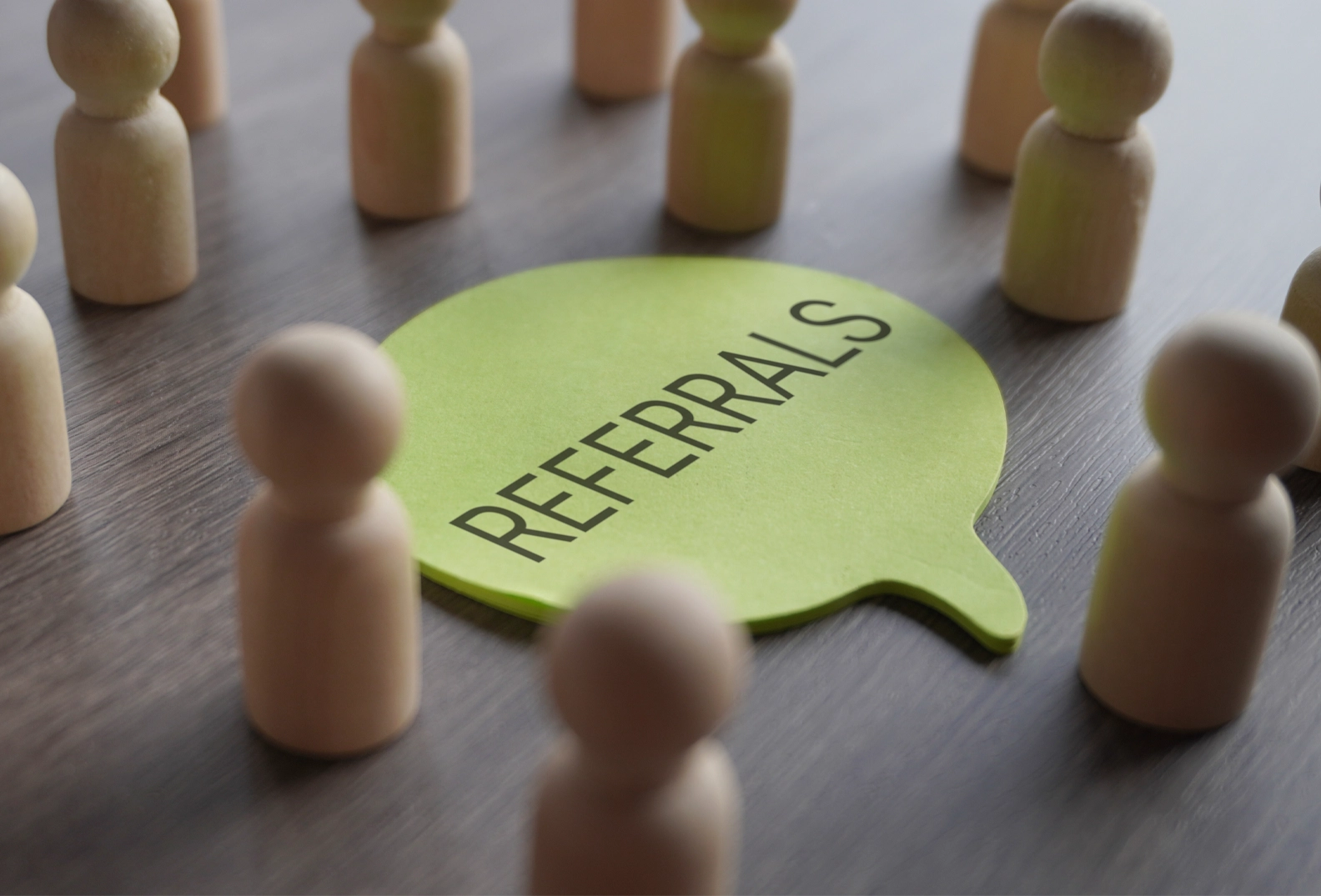 A speech bubble with the words Referrals in it, surrounded by wooden pegs