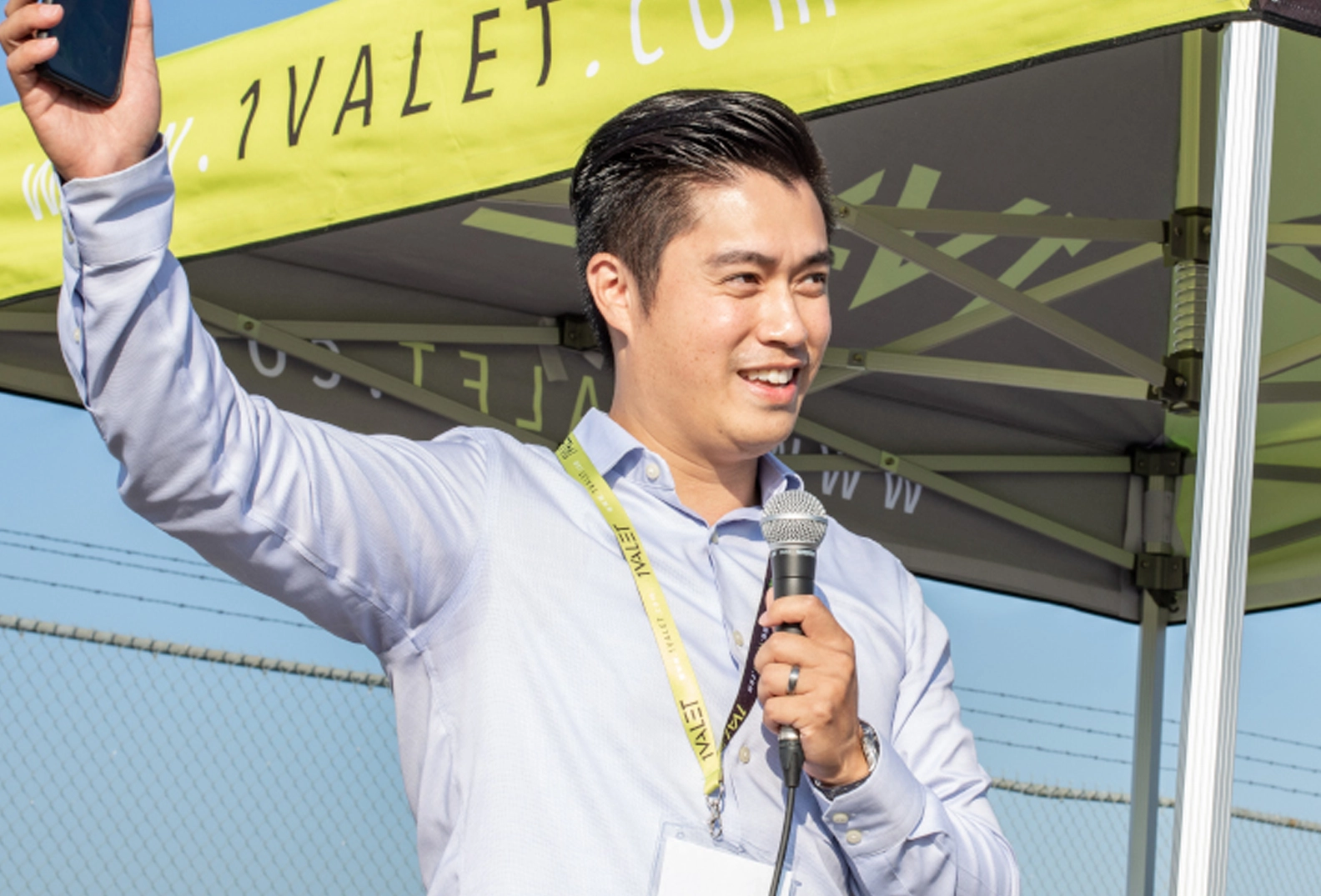 Man speaking at a 1VALET event with a 1VALET event tent behind him