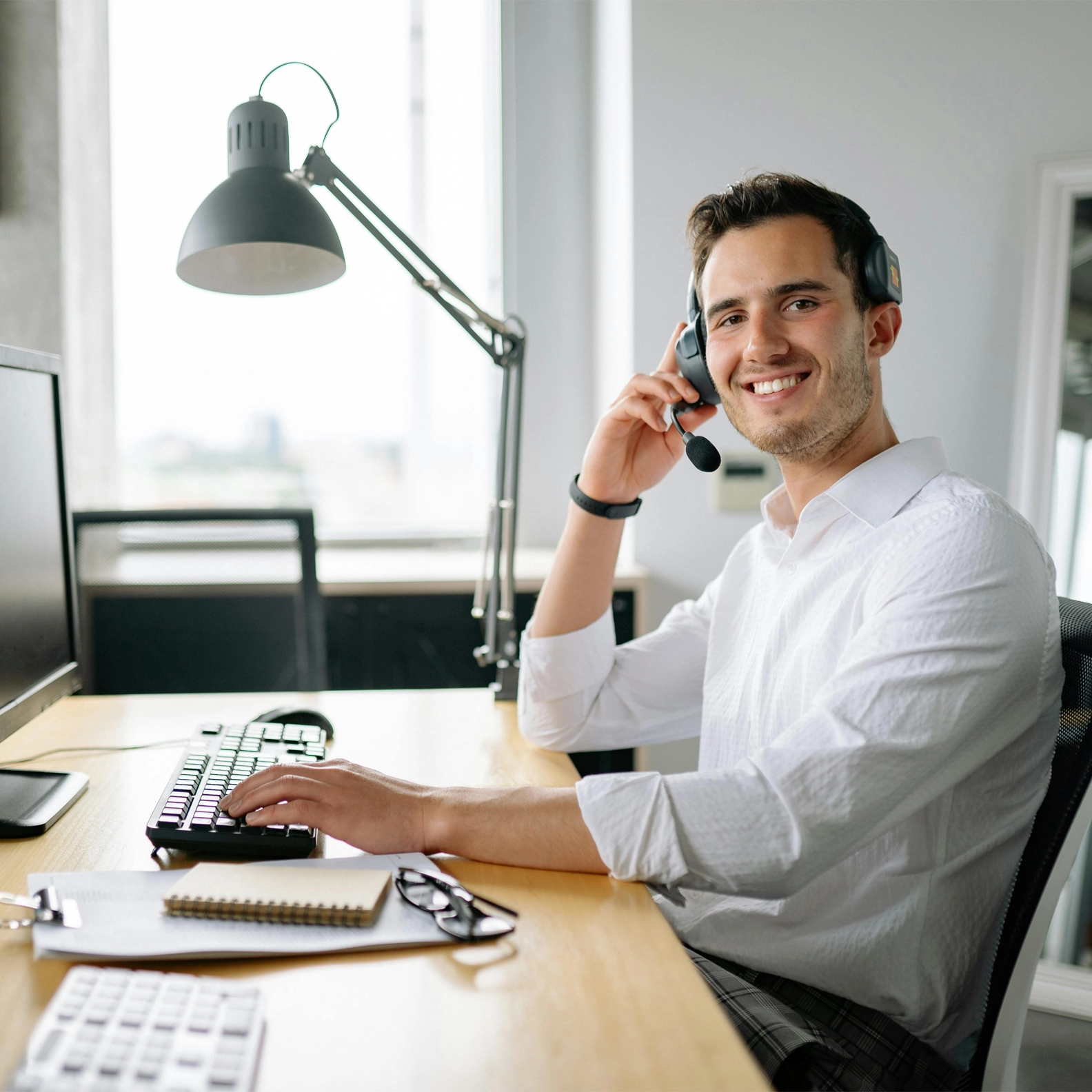 Help desk agent sitting at a computer desk with a headset on