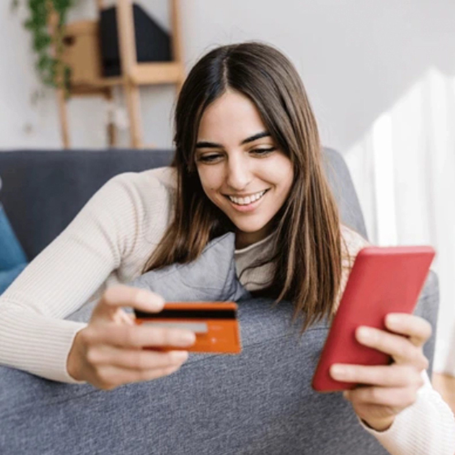 Woman holding a credit card and using her phone to make an online purchase