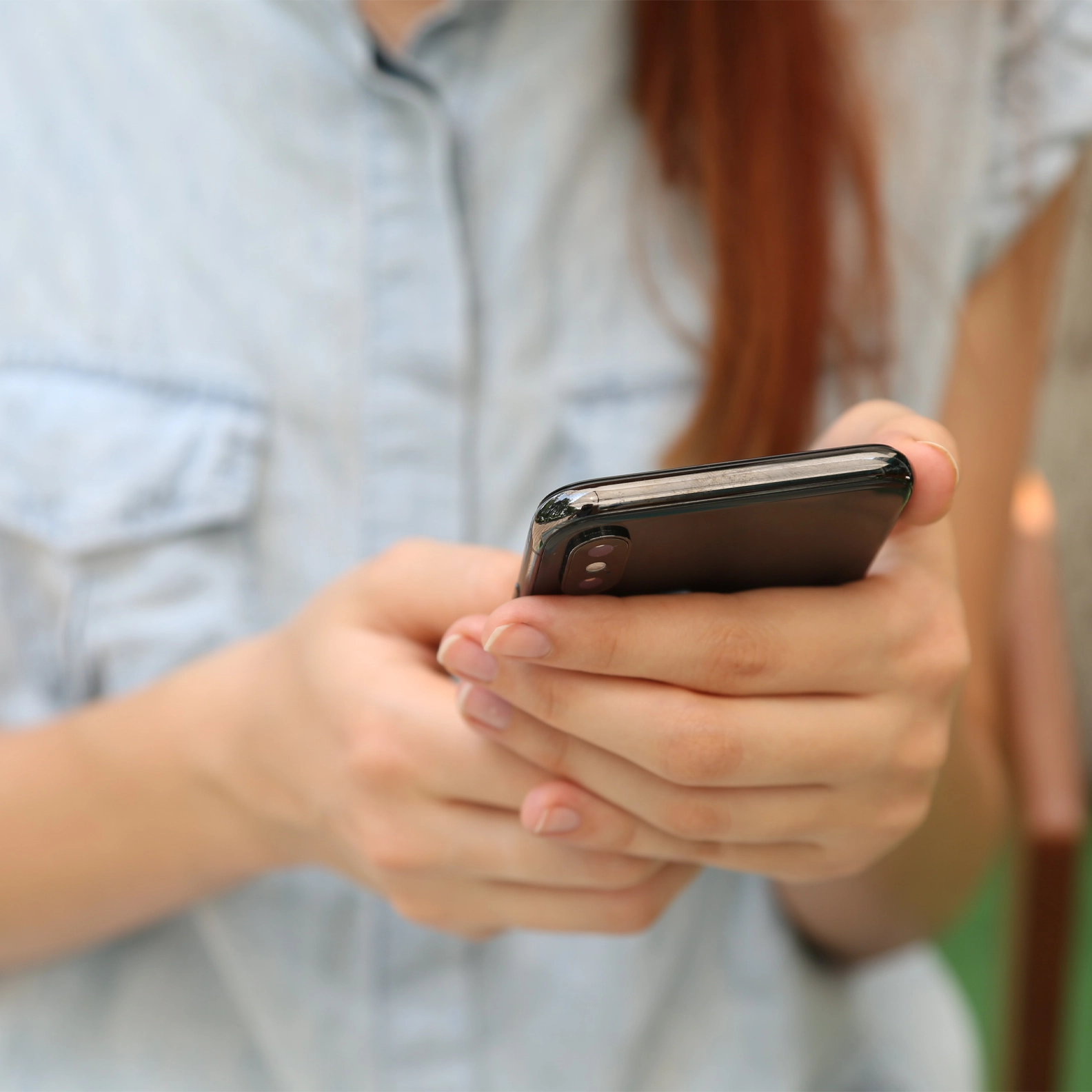 Woman holding her phone in her hands, looking at the screen