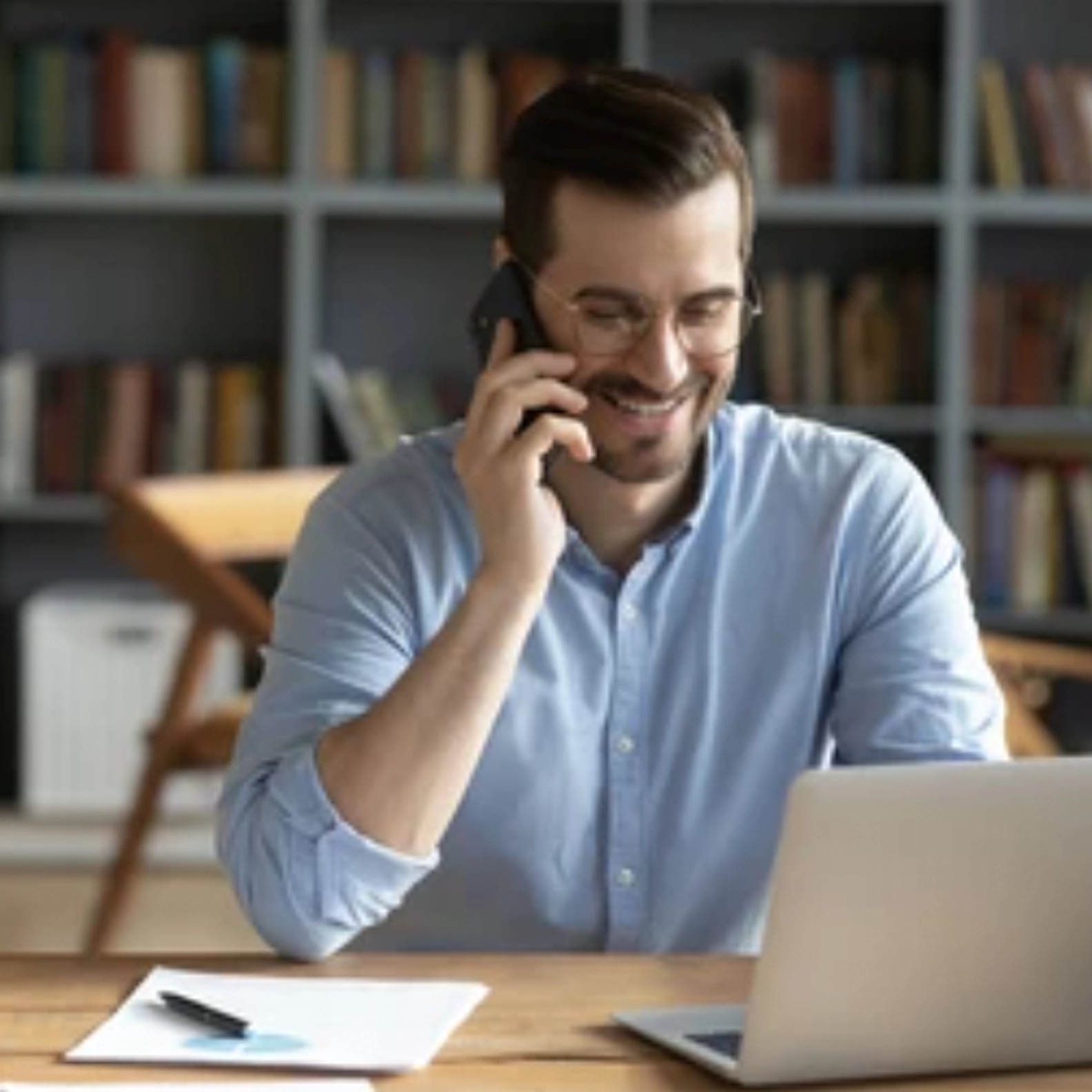 Man talking on the phone smiling while on his computer