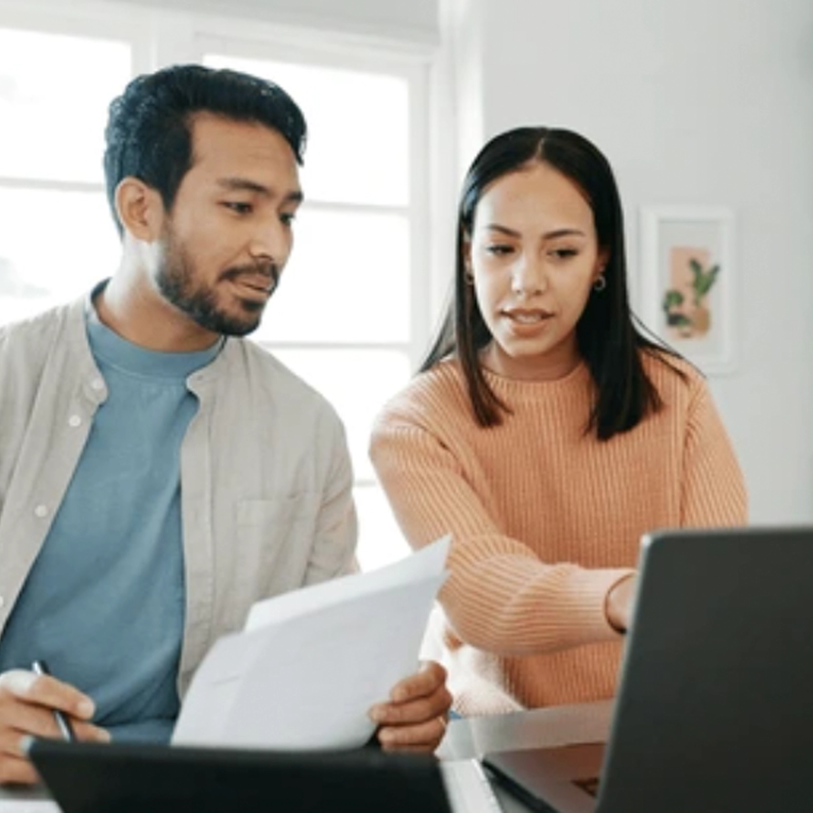 Couple reviewing paperwork while looking at a computer
