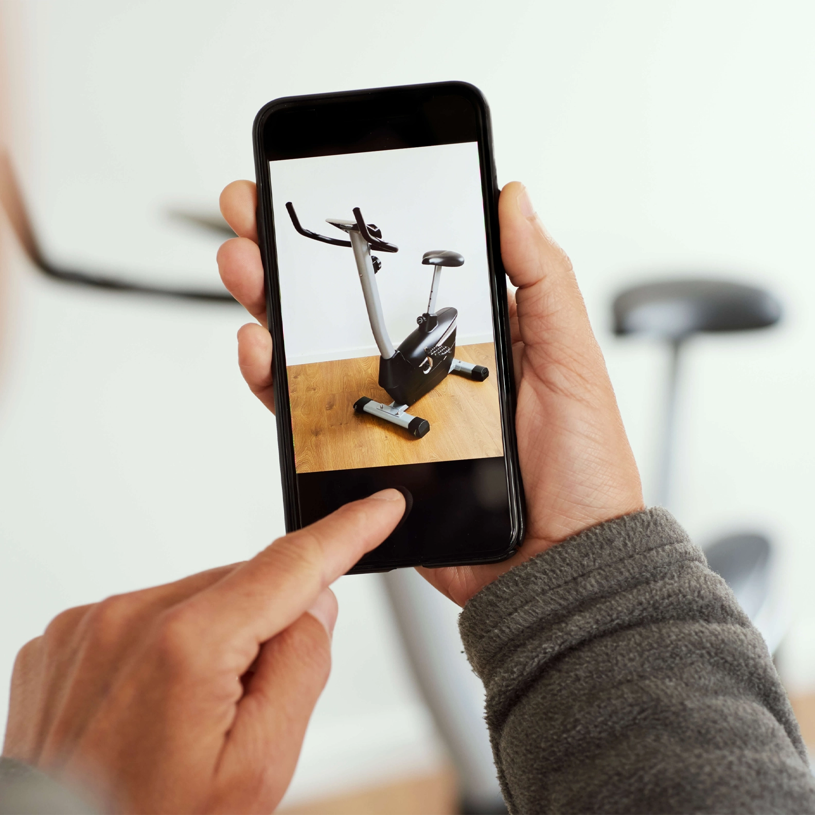 A person using their phone to look at a photo of a stationary bike