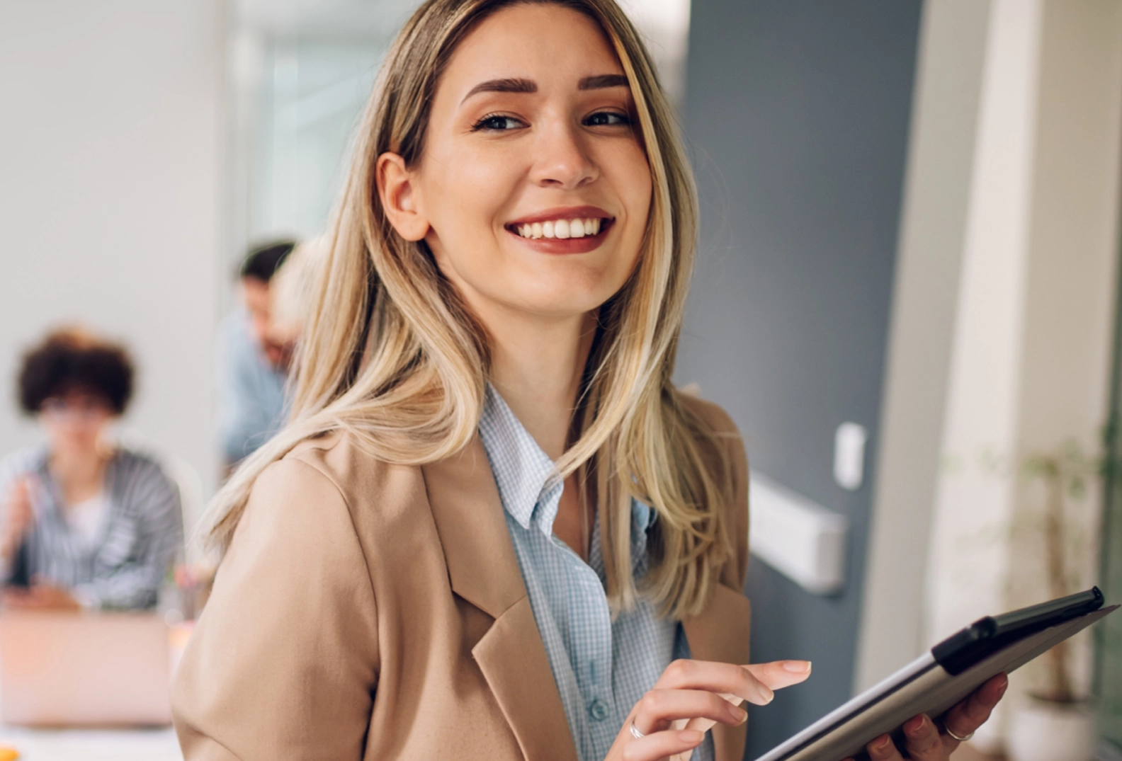 Smiling woman with blonde hair holding a tablet